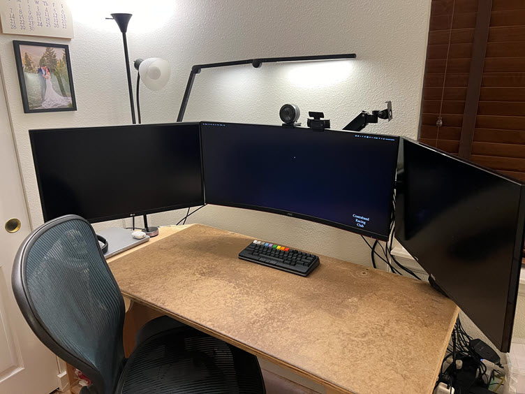 Home desktop setup with three monitors and a HHKB Studio keyboard