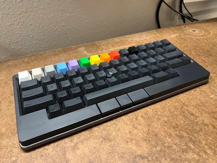 A close up of an HHKB Studio keyboard with a top row of customized, colorful keys