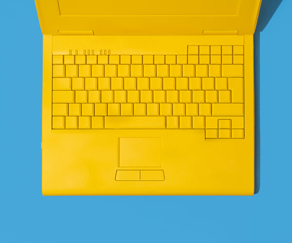 A graphic illustration of a matte yellow laptop with its screen open and legend-less keyboard exposed.