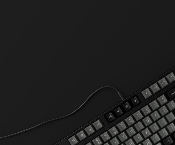A top-down view of a dark grey keyboard on a grey background, with the keyboard's cable trailing off through the negative space in the middle and side of the image.