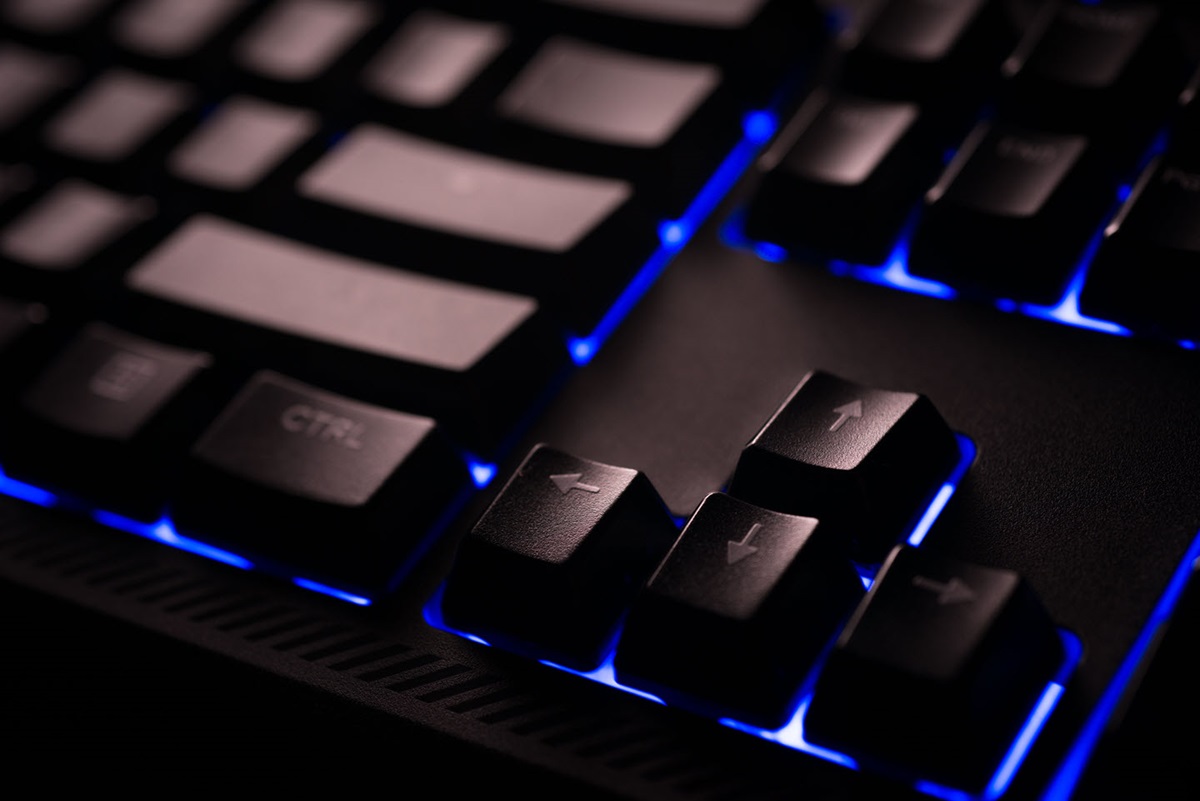 A closeup of a keyboard with glowing blue lights underneath each keycap.