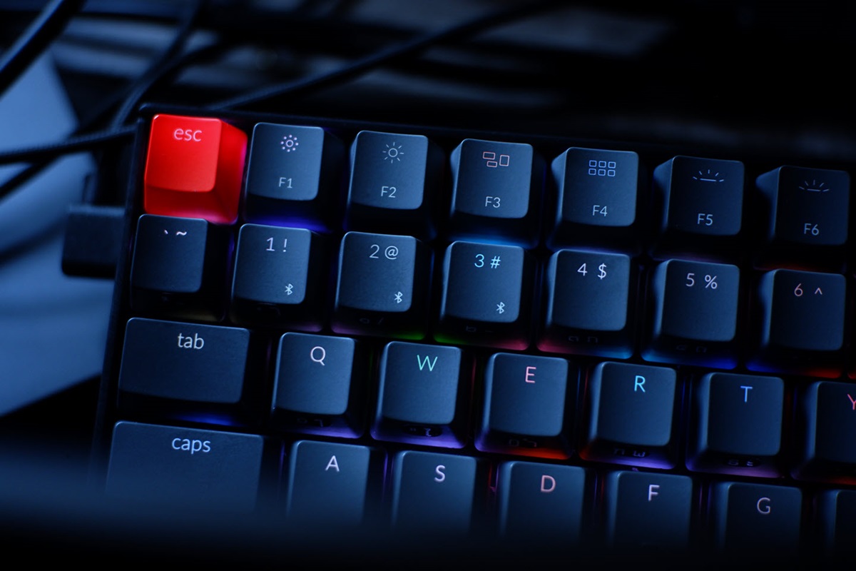 Close up of a black mechanical keyboard with subtle RGB lighting and a bright red escape key.