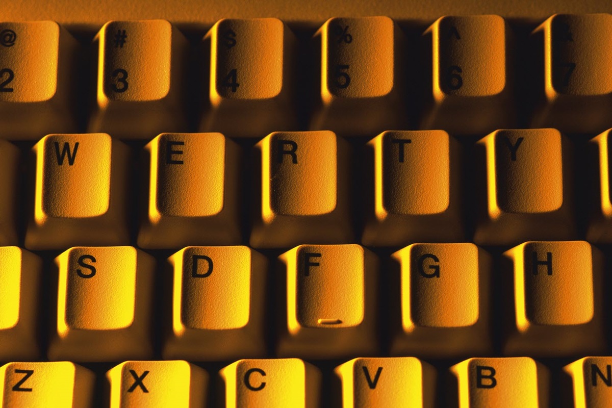 A top-down, close-up of keyboard keys light from the side with a bright orange light.