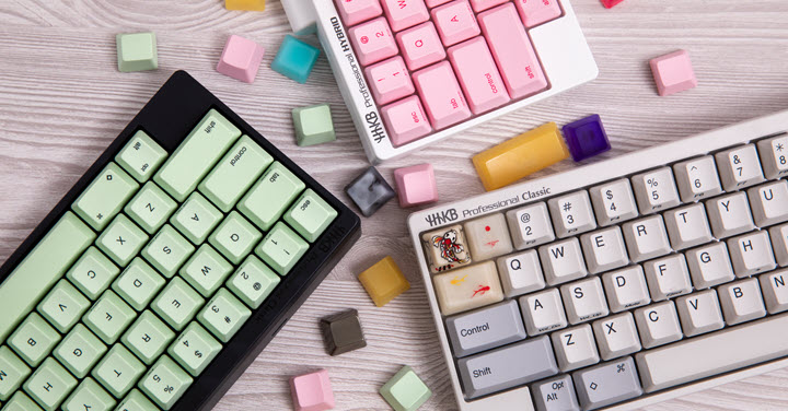 Three keyboards of different colors with keys laying around. 