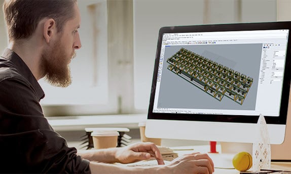 Man sitting at his desk in front of a computer monitor viewing an image of HHKB Studio 3D data. 